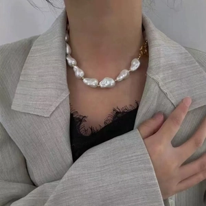 Close-up of irregular Baroque pearl necklace with gold beads on a grey blazer