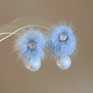 Macro shot of 18K gold plated earring with blue fur ball, zircon and white pearl