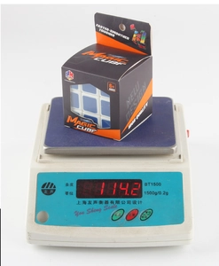 Detail shot of a 3x3 magic cube being weighed on a digital scale showing 114.2g mass