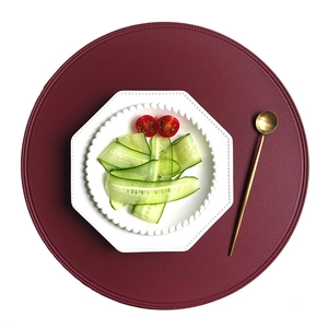 Deep red round PU leather placemat with elegant stitching on white background