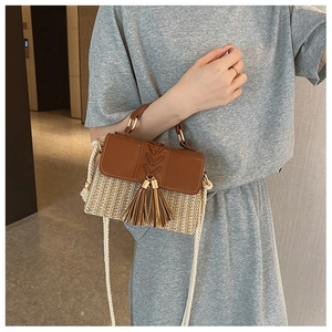 Detail of straw saddle bag with brown leather flap and stylish tassel on grey suit