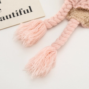 Detail of pink knitted hat showing thick braided tassels and warm fleece lining texture