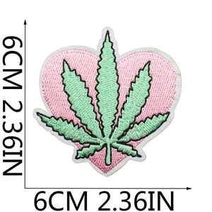 Macro detail of a 6cm pink heart-shaped patch with green embroidery and dense stitching