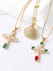 Detailed view of gold necklaces with zirconia cross and seashell shell pendants