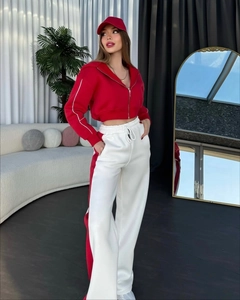 Détail du sweat à capuche rouge et du pantalon large à rayures porté par un mannequin