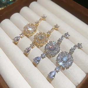 Detailansicht goldener und silberner Blumenohrringe mit Tropfen-Zirkonia in der Box