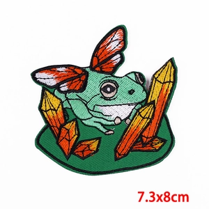 Macro detail of frog with butterfly wings embroidery patch showing fine needlework texture