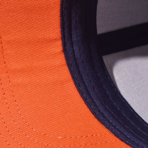 Close-up of orange and navy baseball cap showing durable fabric and reinforced stitching