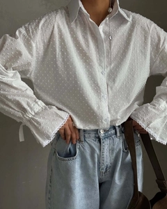 Detail of white long sleeve blouse with polka dot texture and delicate lace cuffs