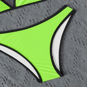 Detail of neon green bikini bottom with black piping and high-elastic fabric texture