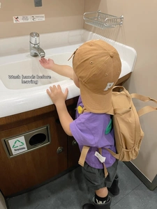 Detailed view of khaki kids baseball cap with P embroidery and matching canvas backpack