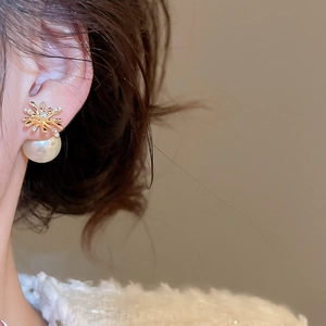 Close-up of gold fireworks earring with pearls and zircons worn on model ear