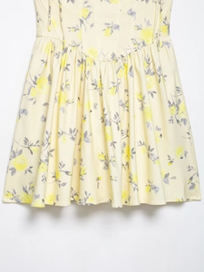 Detail of yellow floral poplin mini dress showing bright flower print and pleated hem