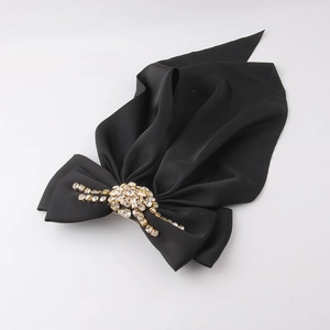 Close-up of black satin bow hair clip with sparkling rhinestone clusters and floral details