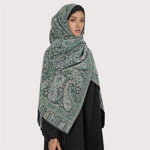 Detail eines grünen Schals aus Kerngarn mit Paisley-Mustern und dekorativen Fransen-Details