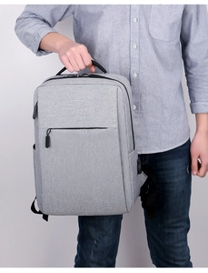 Detail view of grey business laptop backpack featuring side USB port and top handle
