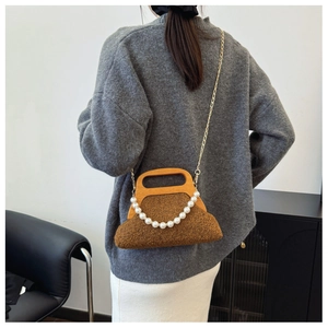 Detail of a brown fuzzy handbag with a wooden handle and elegant pearl chain accent