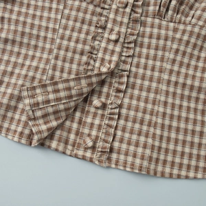 Detail of ruffled front placket with matching buttons on brown plaid shirt fabric