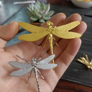 Macro detail of golden and silver metal dragonfly ornaments with intricate mesh wing texture