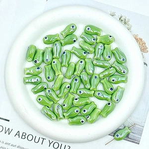 Macro shot of green fish-shaped ceramic beads for DIY jewelry making in a white tray