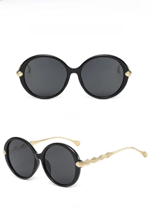 Detailed front and side views of black oversized sunglasses with gold leaf temple texture