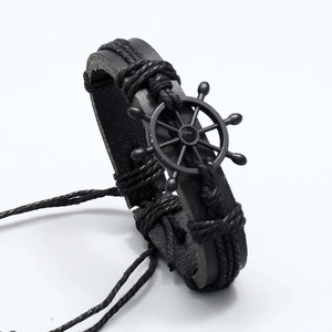 Close-up of black braided leather bracelet with a vintage rudder anchor metal charm