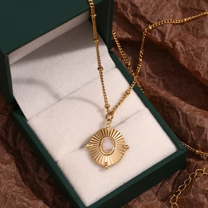 Macro detail of 18K gold plated stainless steel necklace with white crystal on green velvet