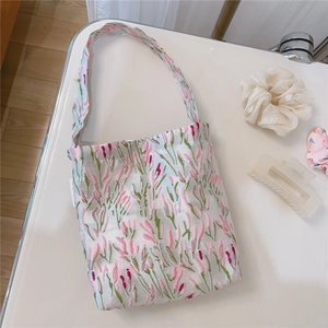 Detailed embroidery view of pink floral heart patterns on a soft beige fabric tote bag