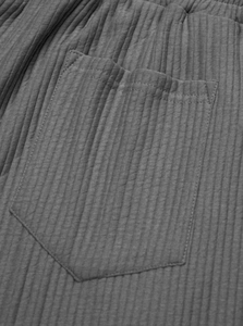 Macro shot of dark grey ribbed knit fabric showing pocket detail and stitching