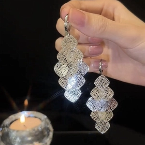 Close-up of silver geometric hollow rhombus fringe earrings with layered mesh design