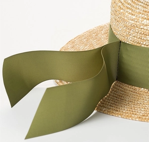 Dettaglio di un cappello di paglia intrecciato a mano con nastro grosgrain verde oliva