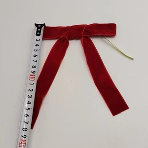 Detail view of a 20cm red velvet Christmas bow with measuring tape for size scale