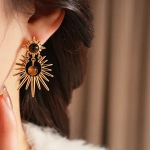 Star-shaped tiger eye earrings with zircon accents and gold-plated finish on model