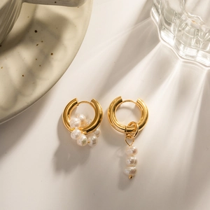 Goldene Creolen mit Barockperlen auf weißem Hintergrund mit eleganten Lichteffekten