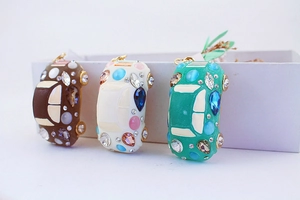Detailed view of three metal car keychains with colorful enamel and sparkling rhinestones