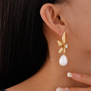 Detail of elegant gold petal earring with zircon and white teardrop pearl on model