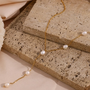 Detail of elegant gold Y-chain necklace with freshwater pearls on stone and pink silk