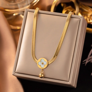 Macro shot of gold-plated flat snake chain with floral shell pendant on beige jewelry box
