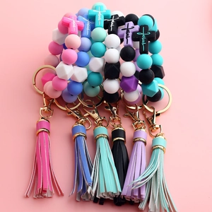 Detail of silicone bead keychain featuring a cross pendant and a matching long tassel