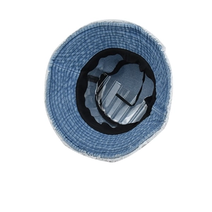 Detailed view of frayed edges on a light blue washed denim bucket hat with sweatband
