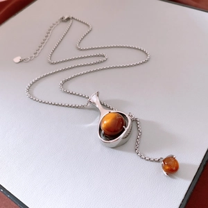 Détail du collier pendentif goutte avec pierres œil-de-chat brunes et chaîne argentée