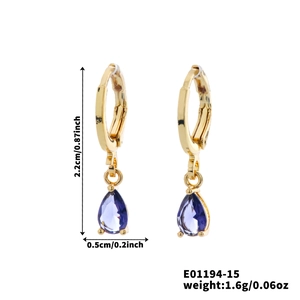 Detail shot of a gold hoop earring with a pear-cut purple gemstone and size markers