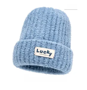 Detail of blue thick knit beanie with rolled edge and white Lucky brand patch text