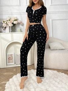Close-up of white heart prints and lace trim on black v-neck pajama set for women
