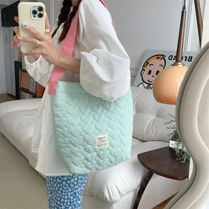Detail of mint green quilted tote bag with heart patterns and pink straps