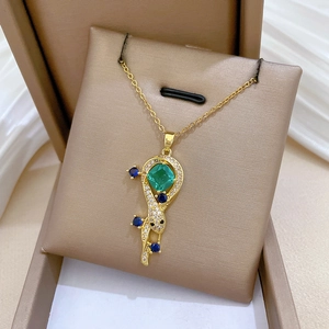 Close-up of golden snake-style necklace with green gemstone and blue crystals in a jewelry box
