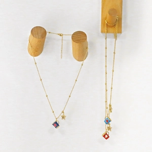 Detailed close-up of gold beaded chains with enamel coffee cup and star pendants