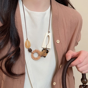 Detail of bohemian geometric pendant with rattan circle, wooden beads and resin accents