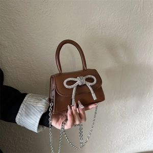 Brown mini crossbody bag with a sparkling silver rhinestone bow and chain strap