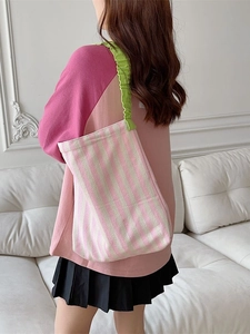 Pink striped canvas tote bag with green ruffled shoulder strap worn by a model